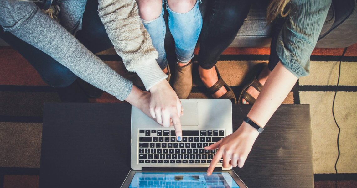 three person pointing the silver laptop computer